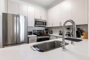 Une cuisine moderne dotée d’appareils électroménagers en acier inoxydable, d’un four à micro-ondes encastré et d’un robinet élégant.