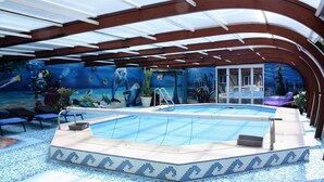 Piscina interna com chão em mosaico e um mural retratando cenas subaquáticas.