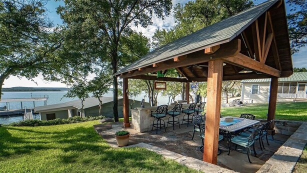 A covered outdoor patio with stone flooring, metal chairs, and a table. - Porch, Paddle & Stay on PK - East side close to Rocker B Ranch (Graford)
