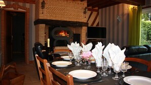 Ein Essbereich mit Kamin aus Backsteinen, Ledermöbeln und einem für eine Mahlzeit gedecktem Tisch.