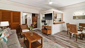 A modern living room with a sofa, coffee table, and dining area with wicker chairs.