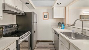 A compact kitchen with a built-in oven, a refrigerator, a sink, and a microwave.