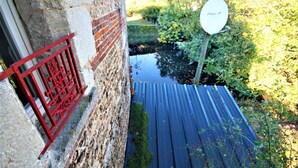 Un étroit sentier extérieur mène à un bâtiment doté d’une porte en métal rouge et d’une antenne parabolique.