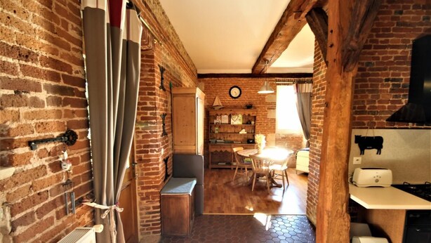 Une cuisine rustique avec des murs en briques apparentes, un banc en bois et une table à manger avec des chaises.