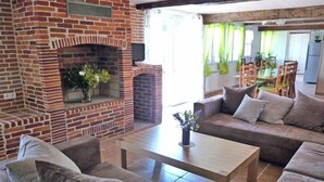 A living room with a brick fireplace, a sofa, a coffee table, and a dining area in the background.