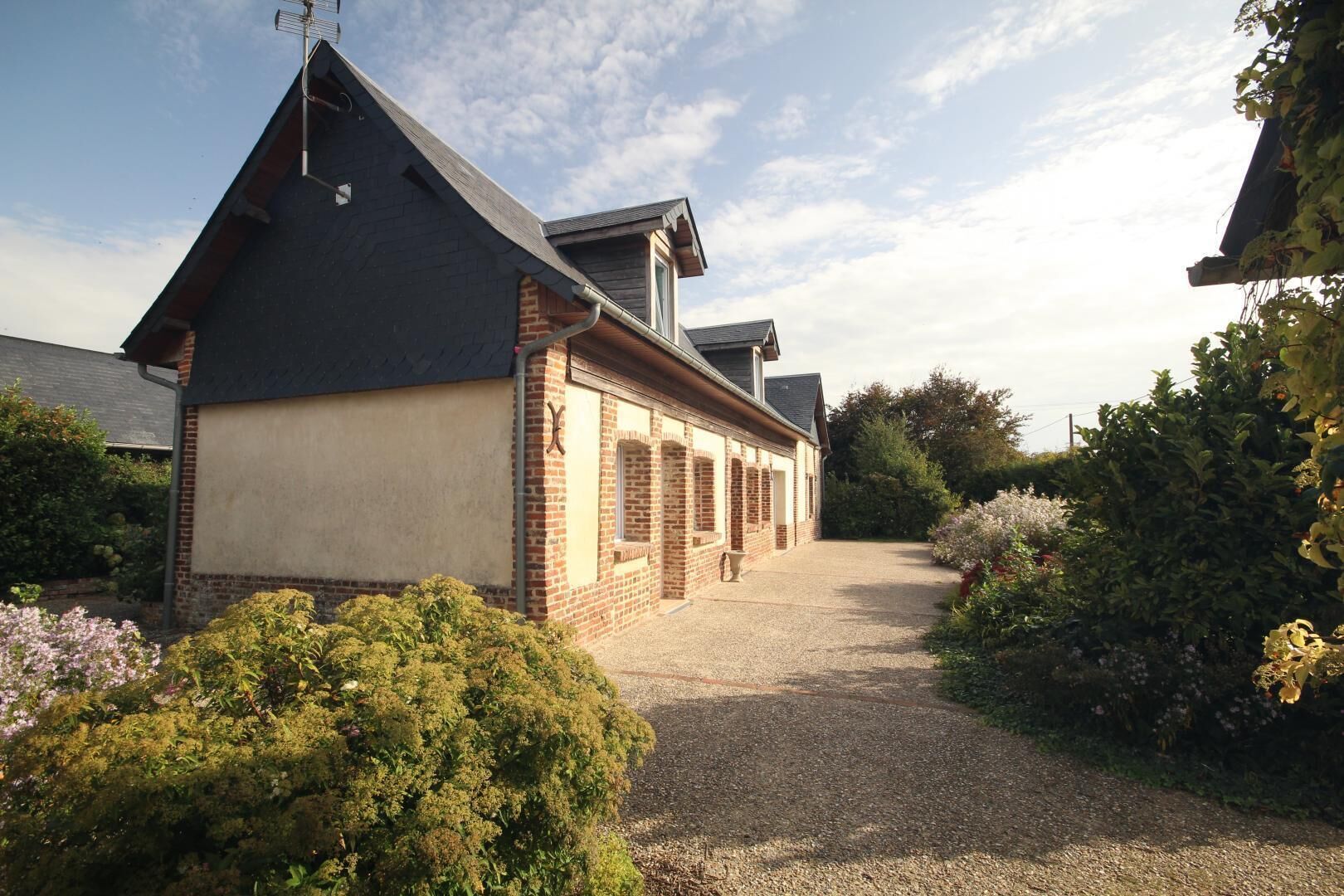 A building with a sloped roof, brick walls, and a gravel driveway.