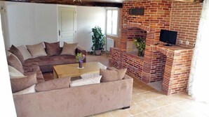 A living room with a brick fireplace, a sofa, and a television.
