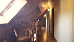 A narrow hallway with wooden walls and a sloped ceiling, leading to a door at the end.