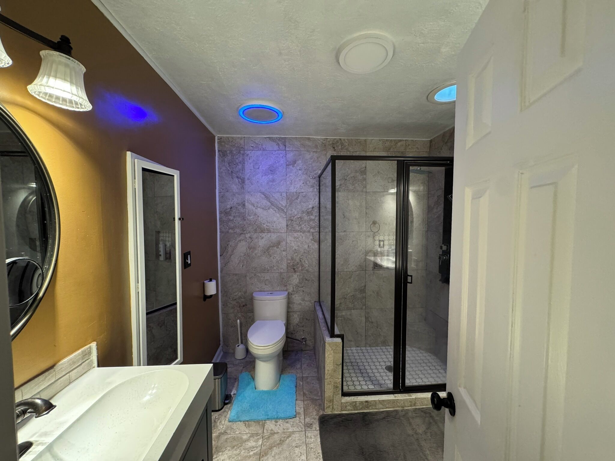 A bathroom with a white sink, toilet, and glass-enclosed shower.
