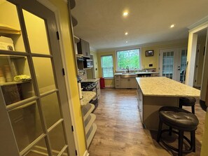 A kitchen with a central island, wooden flooring, and a view of the outdoors through a window. - Spacious 5-bdrm, 4bth with AC, WiFi, fenced yard, outdoor pool in charming Evans (Evans)