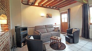 Un salon confortable avec un canapé, deux fauteuils, une petite table et une cheminée.