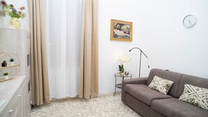A living room with a sofa, a small table with a vase of flowers, a painting on the wall, and a clock. - Minimal and Functional: Stay Near the Vatican (Roma)