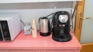 A kitchen counter with a microwave, a coffee maker, a jar of sugar, and stacked paper cups. - Minimal and Functional: Stay Near the Vatican (Roma)