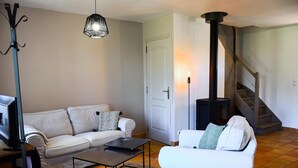 Un salon comprenant un canapé, une table basse, un téléviseur, une cheminée et un escalier.