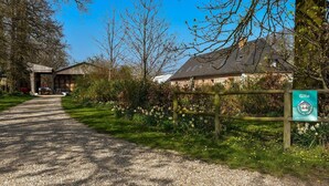 Un chemin de gravier mène à un bâtiment sur lequel est apposée une enseigne indiquant « Gîte ».