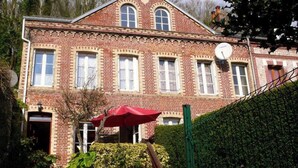 A large brick building with multiple windows and a red umbrella in the foreground.