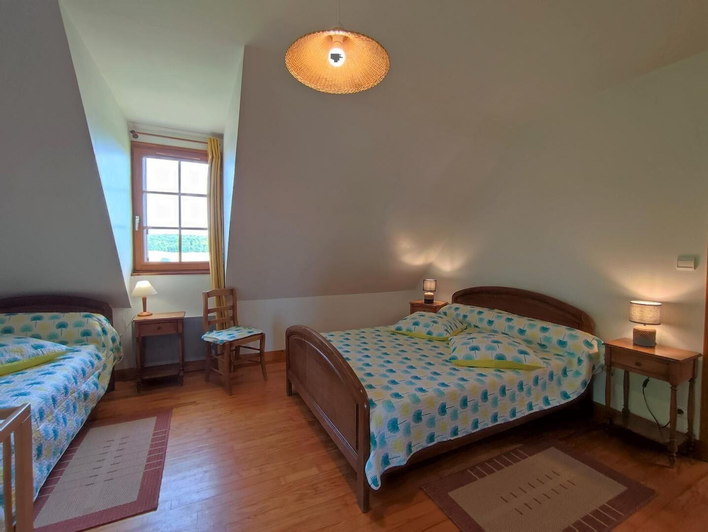 Et soveværelse med to senge, et vindue og en loftlampe.