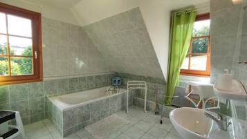 A bathroom with a bathtub, a sink, and a shower area.