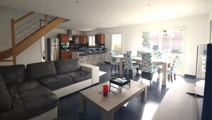 A modern living room with a sofa, a coffee table, and a dining area with chairs and a table.