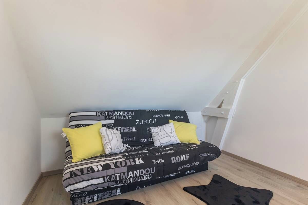 Et lille, kompakt rum med en sovesofa prydet med bynavne og et sort-hvidt mønster.