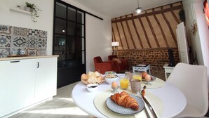 Une table ronde dressée pour le petit-déjeuner, avec des croissants, du pain, des œufs et du jus de fruits.