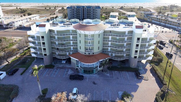 Een meerlaags hotel met een binnentuin, parkeerplaats en uitzicht op het strand.