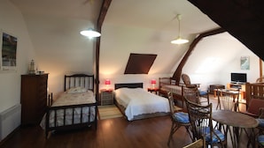 A cozy attic bedroom with two beds, a dining table, and a TV. - Gîtes de France® - La Masûre (ST MARTIN LE GAILLARD)