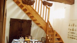 A wooden staircase with a rustic design, a dining table set with chairs, and a wall with a Paris map. - Gîtes de France® - La Masûre (ST MARTIN LE GAILLARD)
