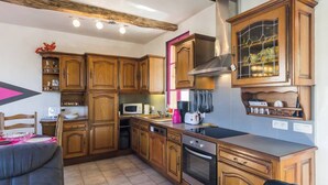 A kitchen with wooden cabinets, a microwave, a stove, and a sink. - Gîtes de France® - The Flowers (CROIXDALLE)