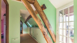 A hallway with wooden beams, a green wall, and a window with a view. - Gîtes de France® - The Flowers (CROIXDALLE)