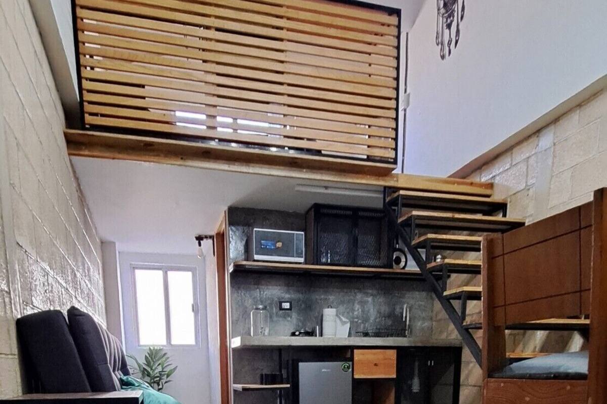 Un espace de vie compact comprenant un canapé, une table à manger et un coin cuisine.