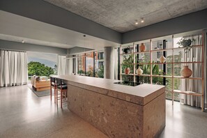 Une cuisine moderne dotée d’un îlot central, de grandes fenêtres et offrant une vue sur la verdure.