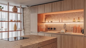 Eine moderne Küche mit Holzschränken, einer Marmorarbeitsplatte und einer eingebauten Ablagefläche mit diversen Küchenutensilien.