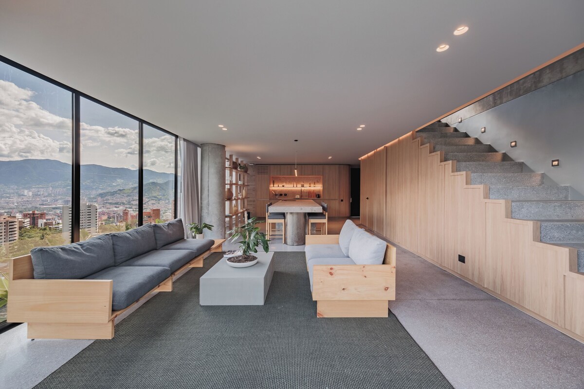 Un salon moderne avec un canapé, une table basse et un escalier.