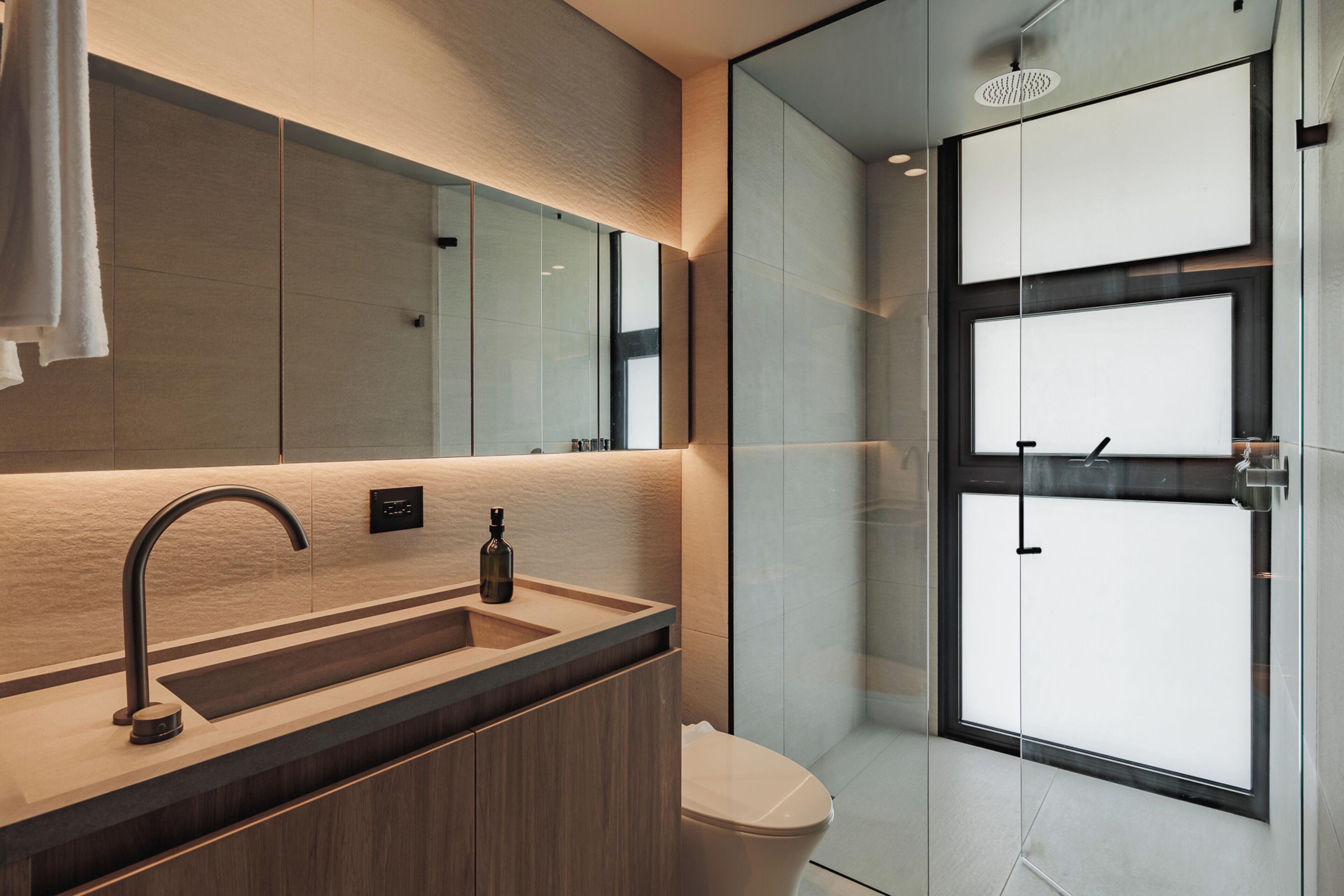 A modern bathroom with a large mirror, a sink with a faucet, and a toilet.