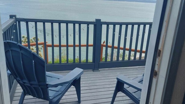 Een balkon met uitzicht op zee, met een houten terras en twee stoelen.