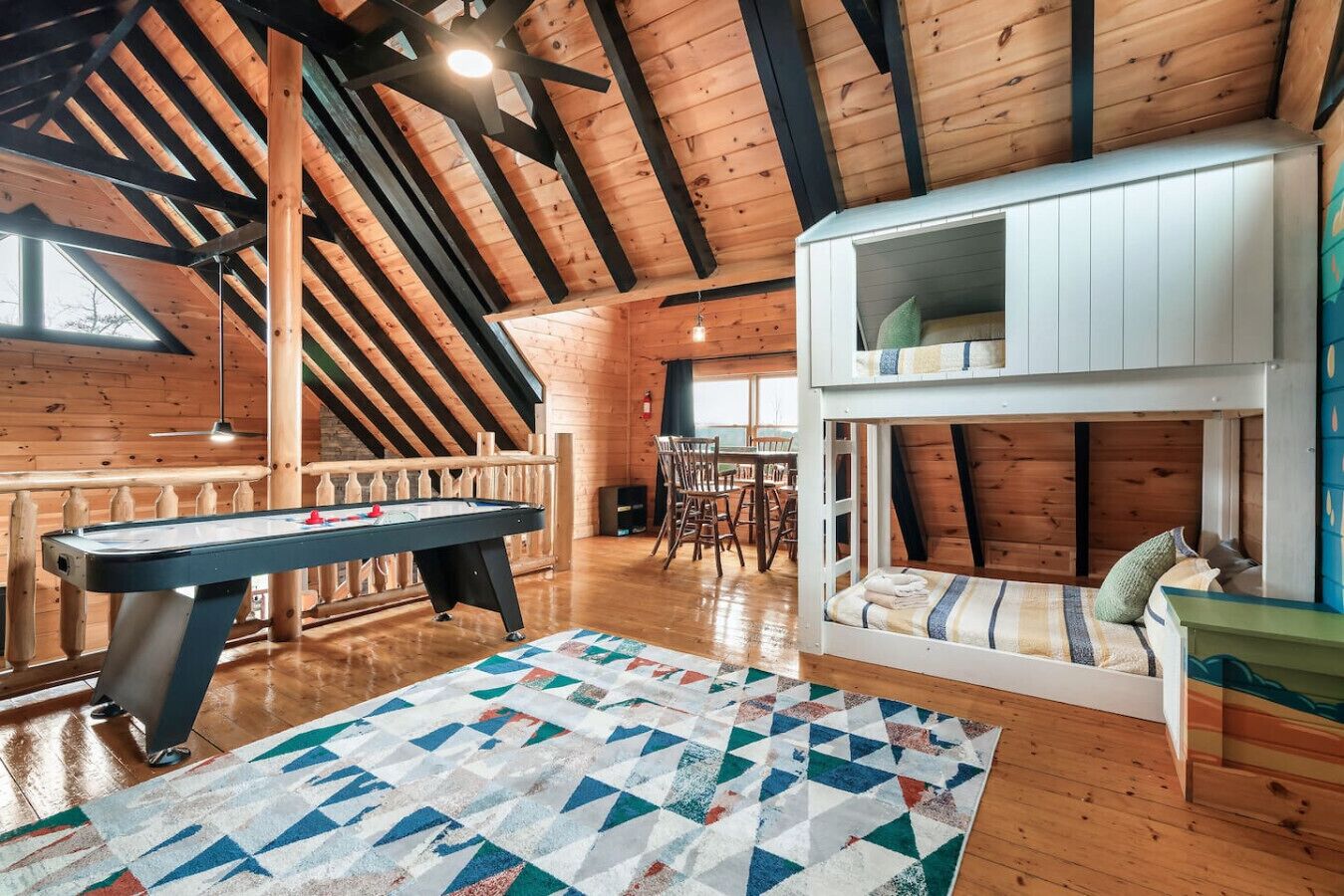 A cozy room with a pool table, a loft bed, and a dining area.