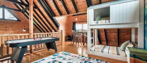A cozy room with a pool table, a loft bed, and a dining area.