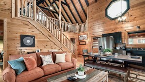 A cozy cabin interior with a wooden staircase, a dining area, and a kitchen. - Spring Break Retreat: Gorgeous Views, Sauna & Spa (Sevierville)