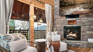 A cozy outdoor seating area with a stone fireplace, comfortable seating, and a view of a natural landscape. - Spring Break Retreat: Gorgeous Views, Sauna & Spa (Sevierville)