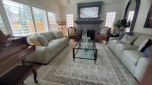 A living room with a piano, two sofas, a coffee table, and a fireplace. - Stunning 4-br, 4-bath brick, and stucco luxurious retreat in Reno Old Southwest. (Reno)