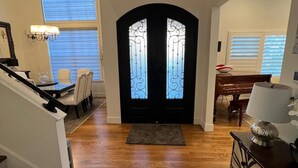 A spacious foyer with a wooden floor, a staircase, a dining area, and a black-framed door with decorative glass panels. - Stunning 4-br, 4-bath brick, and stucco luxurious retreat in Reno Old Southwest. (Reno)