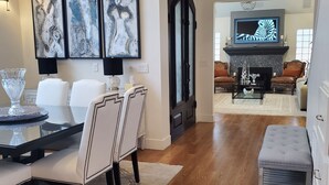 A spacious living room with hardwood floors, a dining area with a glass-top table, and a fireplace. - Stunning 4-br, 4-bath brick, and stucco luxurious retreat in Reno Old Southwest. (Reno)