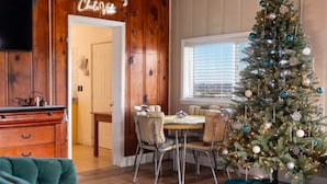 A cozy dining area with a wooden wall, a Christmas tree, and a green sofa. - Incredible Views! Historic Branson Home, two Porch Swings (Branson)