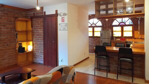 A cozy kitchen with a brick wall, wooden cabinets, and a window with a view.