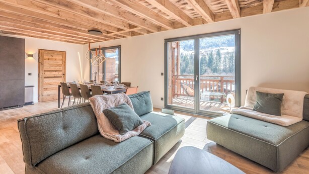Ein modernes Wohnzimmer mit Holzboden, einer Couch, einem Couchtisch und einem Essbereich mit Stühlen und einem Tisch.