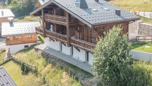 Eine Holzhütte mit Balkon, umgeben von Grünflächen und weiteren Gebäuden.