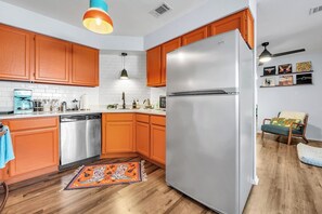 A kitchen with wooden cabinets, a stainless steel refrigerator, a coffee maker, and a dishwasher.