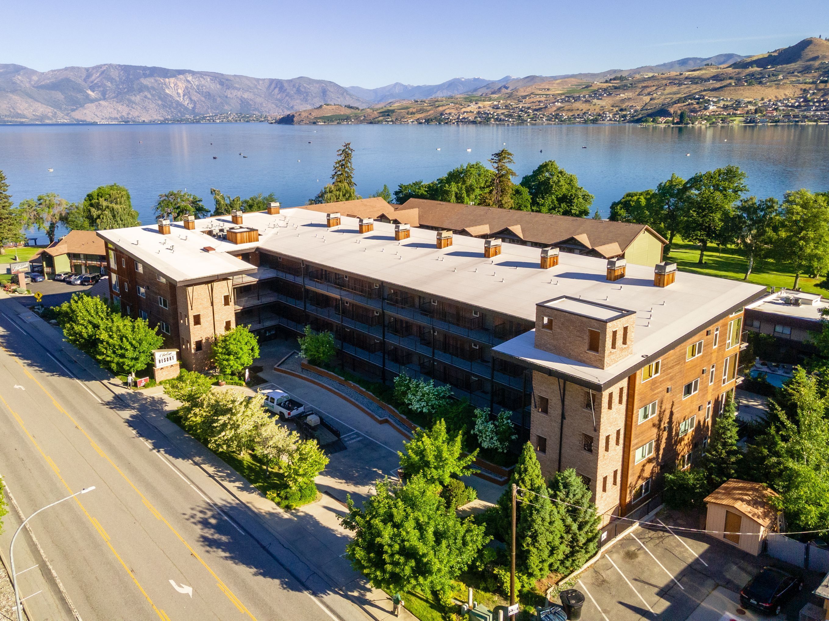 A multi-story building with a flat roof, surrounded by trees and a parking lot.