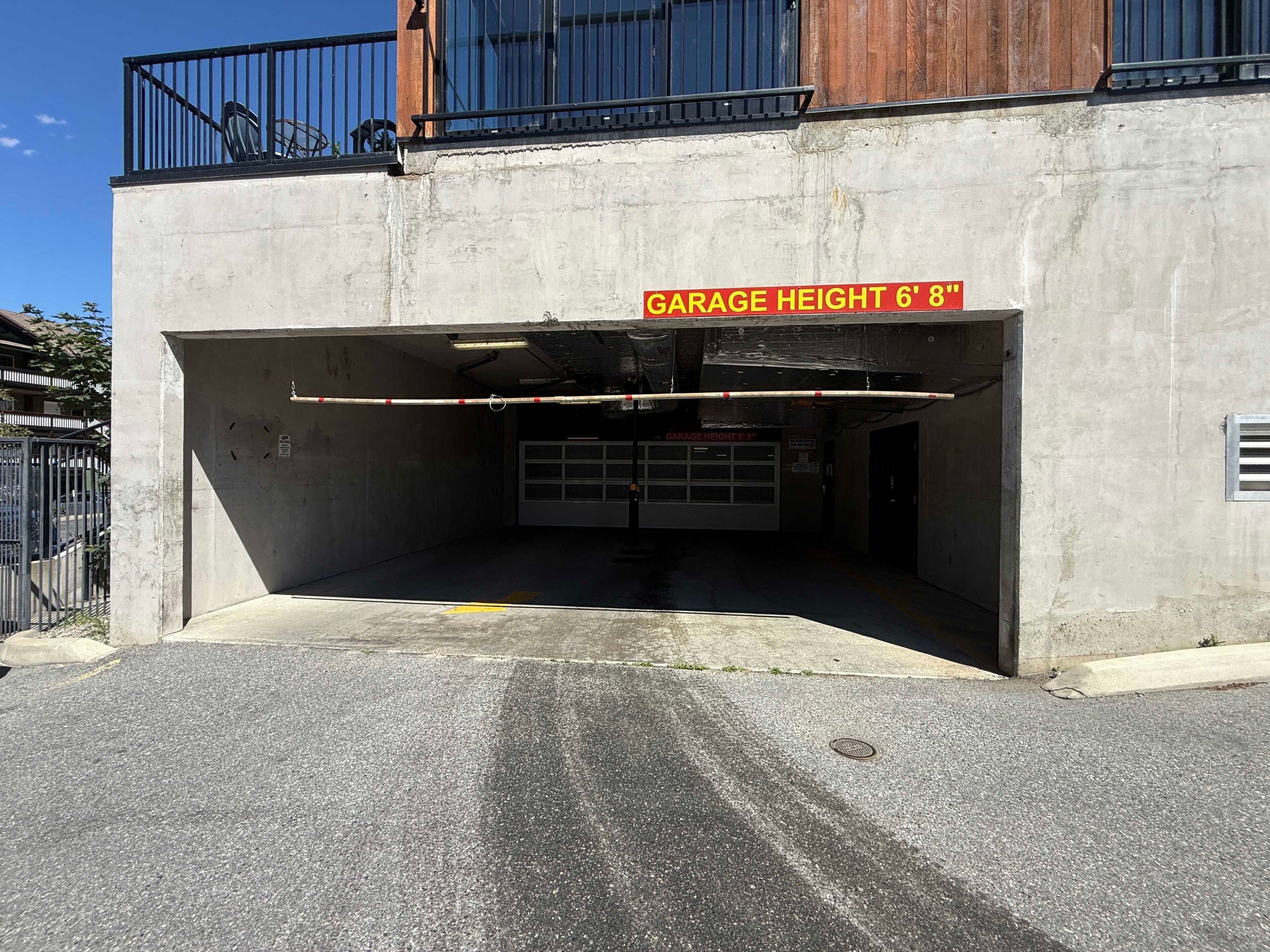 A garage entrance with a height restriction sign, a concrete wall, and a metal gate.